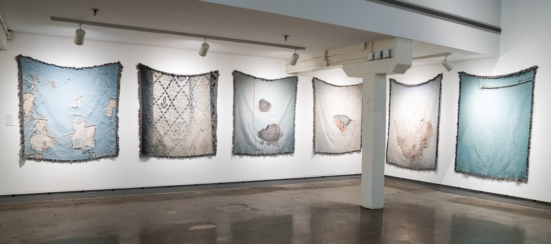 six woven tapestries that depict chipping wall paint displayed on the wall