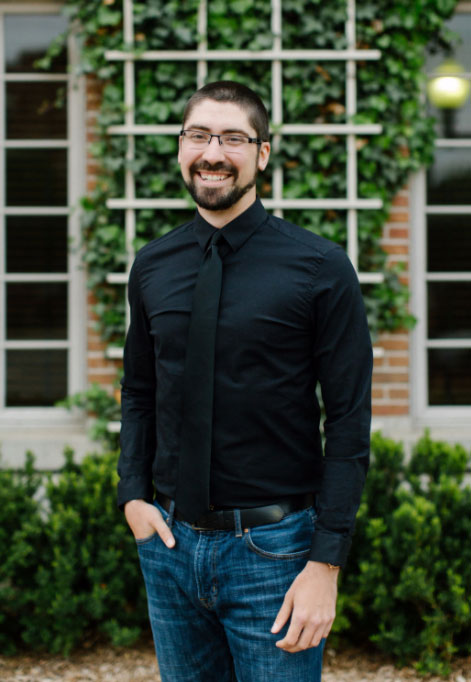 man in a dark button down shirt, smiling