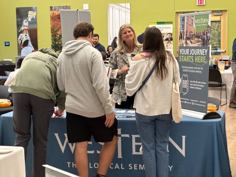 Students leaning on table Ministry and Christian Grad School Fair