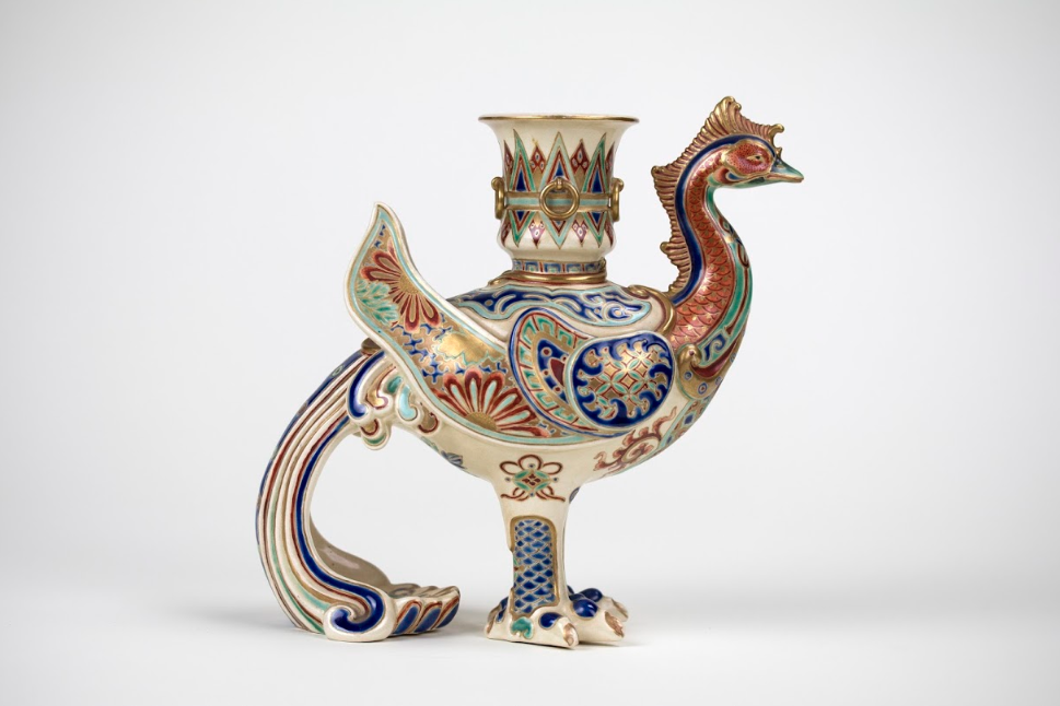 An ornate white vase in the shape of a bird with colored details
