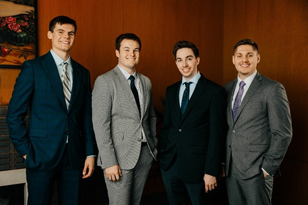 4 young men in suits  smiling together