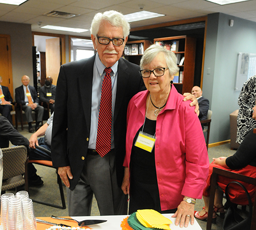An older man and woman standing together, both have glasses